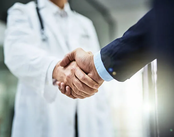 A healthcare professional and business partner shaking hands