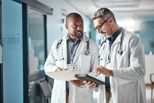 Two physicians reviewing provider credentialing records on a tablet